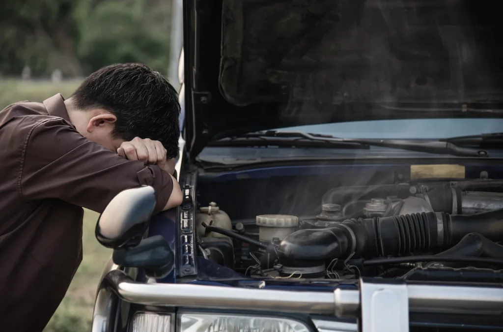 man try to fix a car engine problem on a local road